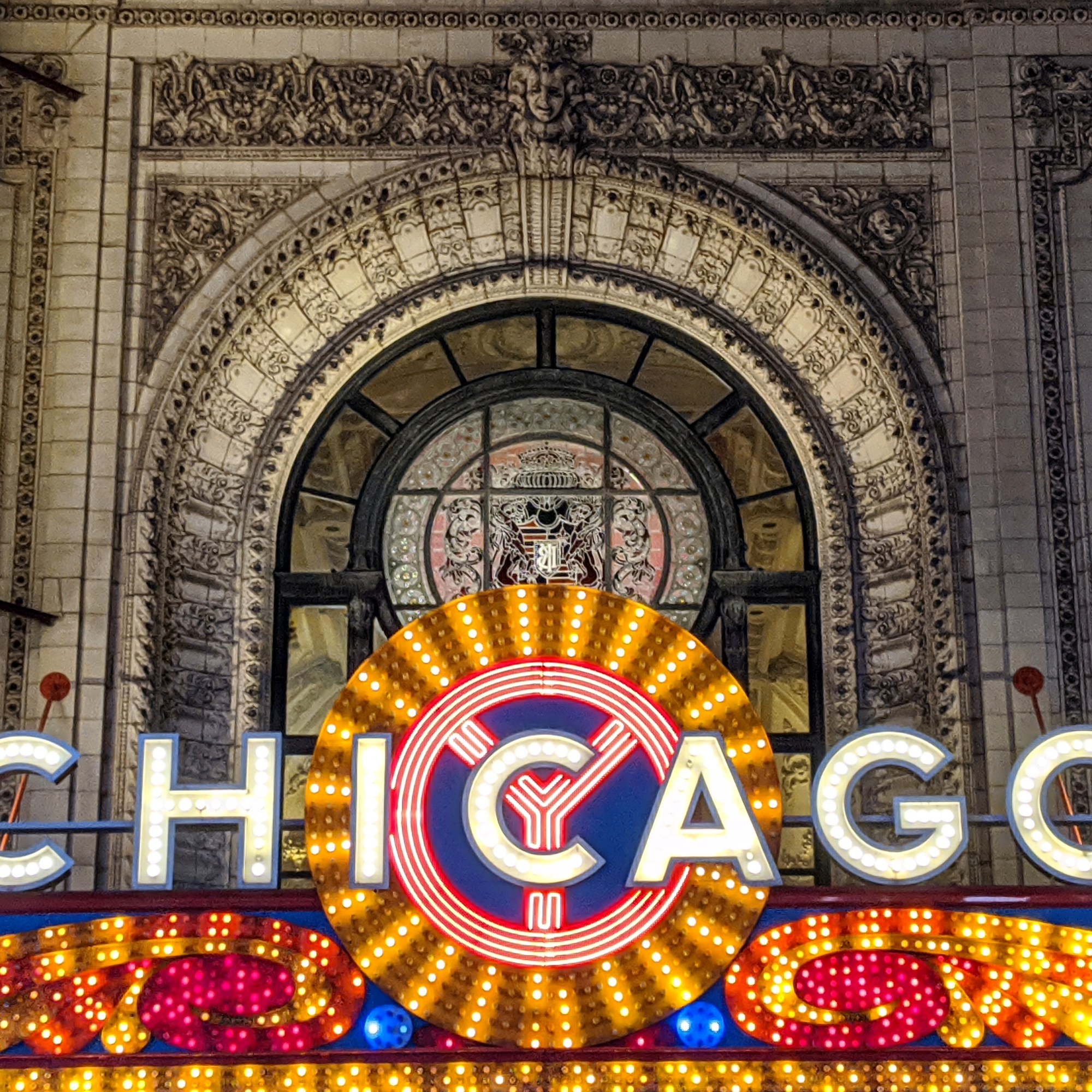 Illuminated Chicago theater sign with ornate architectural background.